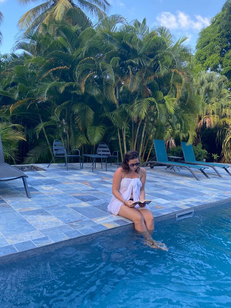 Une personne les pieds dans l'eau de la piscine extérieure au Caraïb'Bay Hôtel