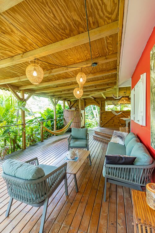 Vue de la terrasse avec canapés d'extérieurs et un hamac de la villa Kariakou du Caraïb'Bay Hôtel
